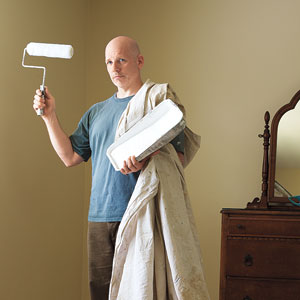 TOH editor, Scott Omelianuk draped in a drop cloth holding a paint roller and tray