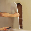 cutting into drywall between beams to make space for niche