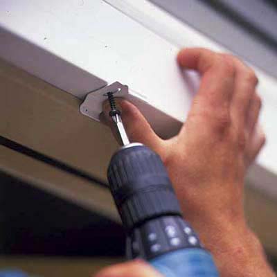3. Fasten two metal mounting clips to the head casing over the doorway. Use one screw per clip.