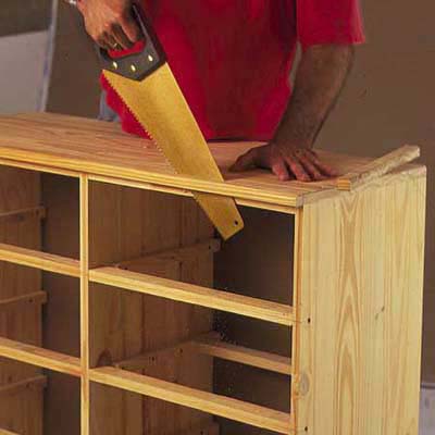 using a handsaw to trim the ends off of a dresser