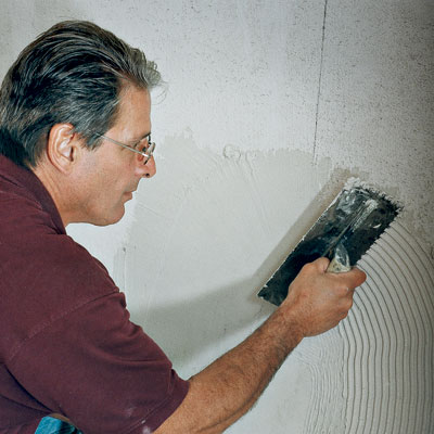 tiling contractor Mark Ferrante spreads thinset with a square-notched trowel