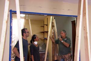 contractor showing homeowners how to set up a dust barrier system using spring loaded poles
