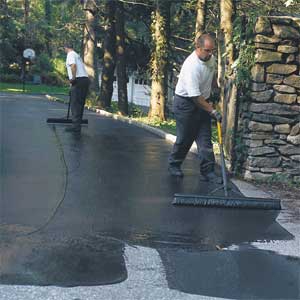 men applying sealant to an asphalt driveway