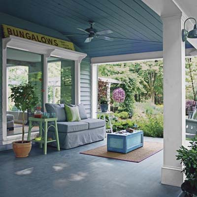 outdoor living area with comfortable sofa, center table, and porch swing with large throw pillows
