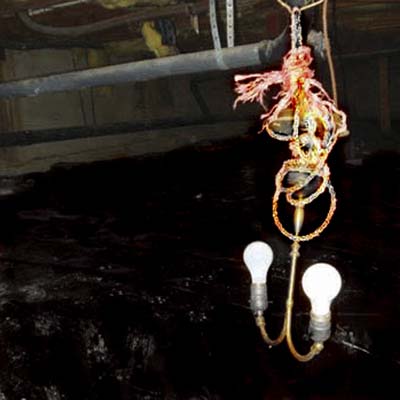 chandelier with exposed bulbs hanging in crawlspace