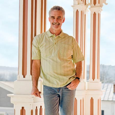 homeowner Vic Young leaning against a porch column of his restored Italianate house