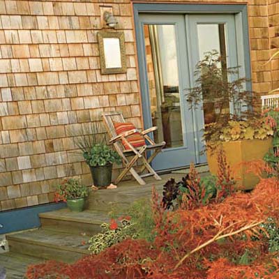 wood deck attached to shingled house featuring container gardens with foliage and colorful plants