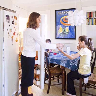 homeowner standing before her open refrigerator demonstrating how tight a fit the current kitchen configuration is