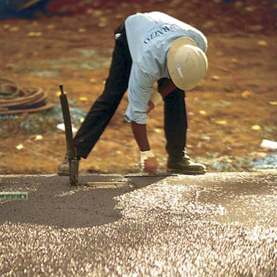 man bending low to trowel