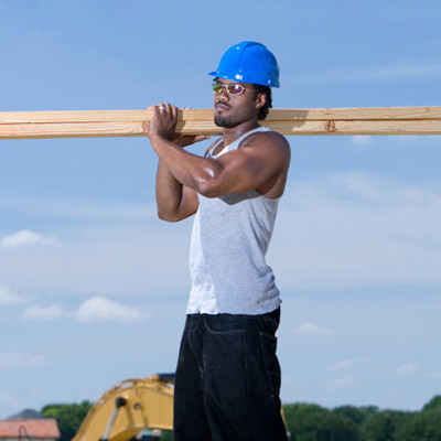 contractor with big muscles lifting wood planks