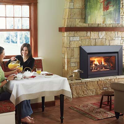 two women pouring juice at a table next to a gas fireplace