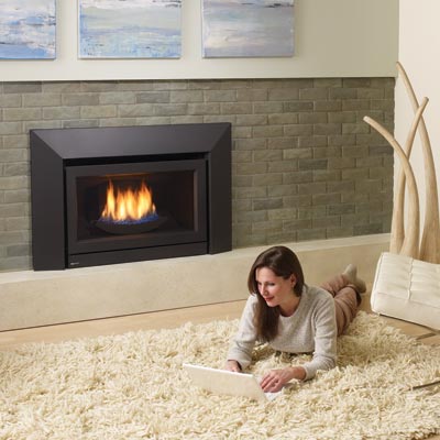 woman lying on a thick shag rug with a laptop in front of a gas fireplace
