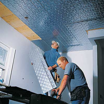 two people installing panels for the tin ceiling