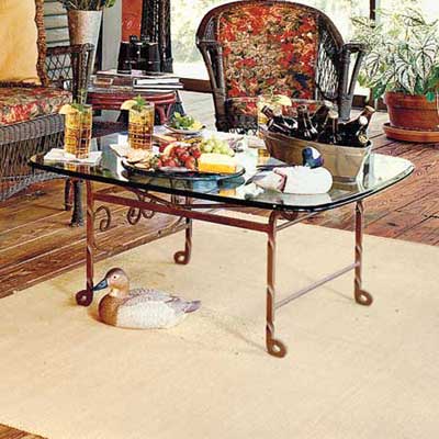 rusted iron and glass table and sisal rug on porch