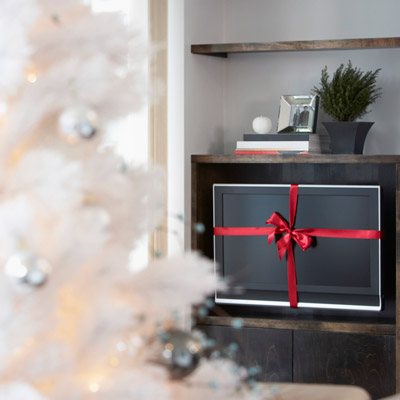 tv with red ribbon next to christmas tree