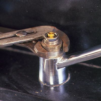 man using pliers to free retainer nut of faucet