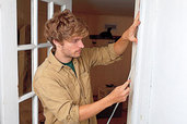 person installing weather stripping to a door