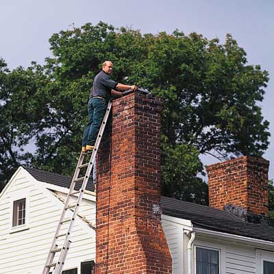 man putting cap on chimney to keep critters out
