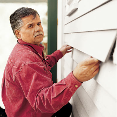 man replacing rotted wood siding