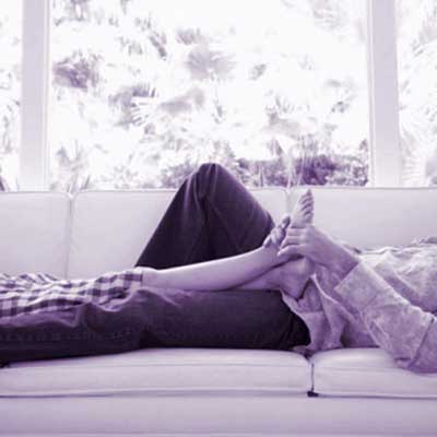 man massaging woman's feet on couch
