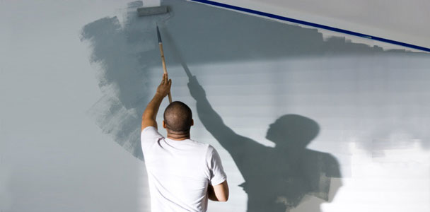 man painting wall with roller