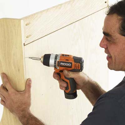man using a drill/driver to reinforce the back of a built-in bench