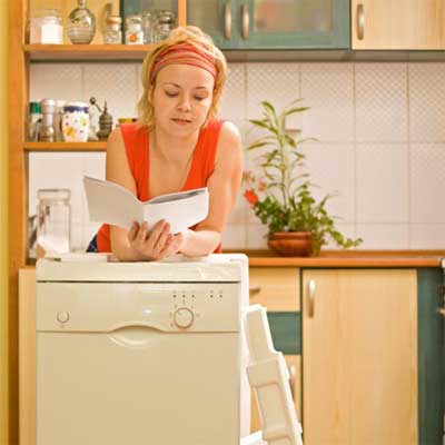 person standing over an un-installed appliance reading a manual