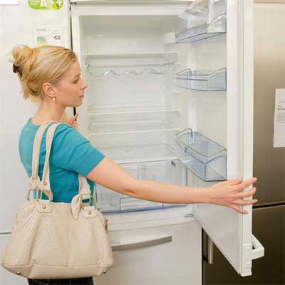 shopper examining the way a refrigerator door opens and closes