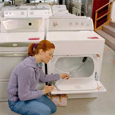 two people holding a specifications sheet and examining the front of a washer dryer