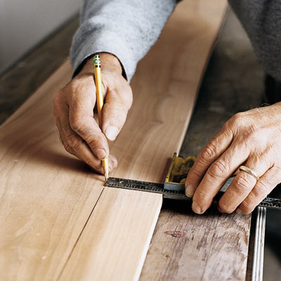man using square to mark piece of wood