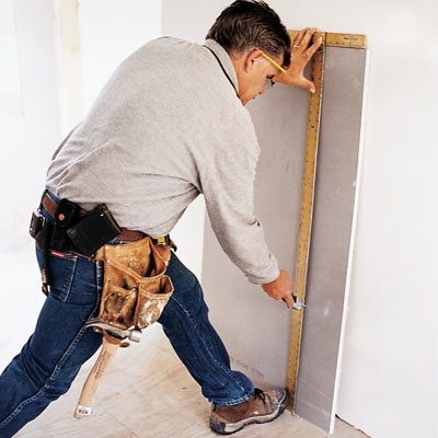 man using drywall square to cut drywall