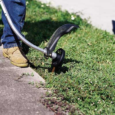 man using string trimmer to edge
