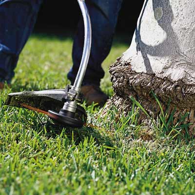 man using string trimmer to edge around step