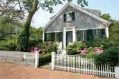 beautiful white picket fence in front of a house and flower garden