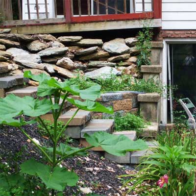 lopsided deck resting on a retaining wall that is falling over