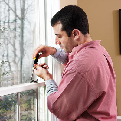 man fixing window that rattles in the wind
