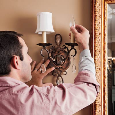 man screwing in sconce bulb