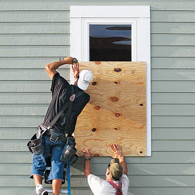 two men boarding up windows in preparation of storm