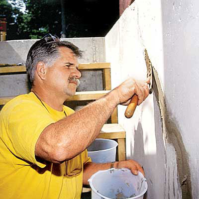 Tom Silva applies hydraulic cement to a foundation wall
