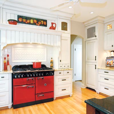 old world style kitchen with white cabinetry and red range