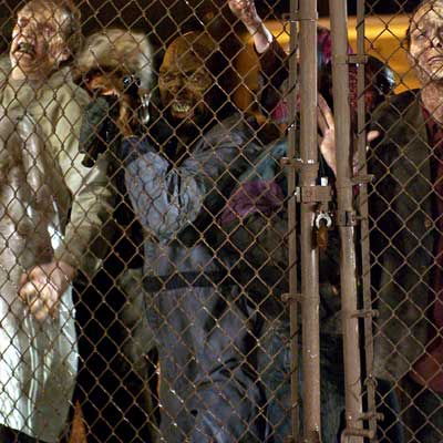 land of the dead scene of zombies in front of chain link fence