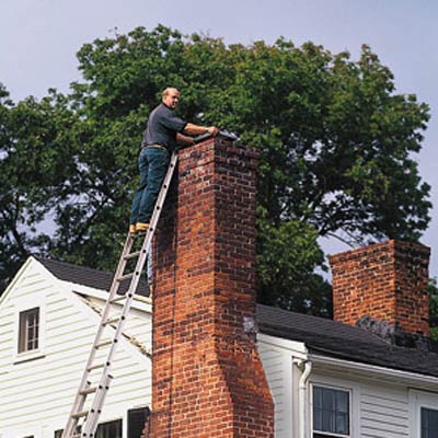 A man on a ladder repairing a chimney