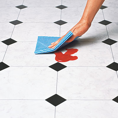 hand wiping up spill on vinyl flooring
