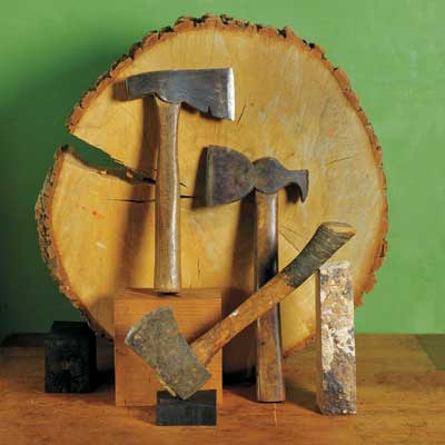 collection of hatchets leaning against a tree round