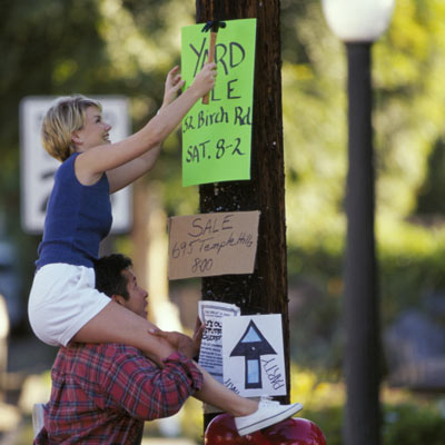 couple nailing up yard sale sign