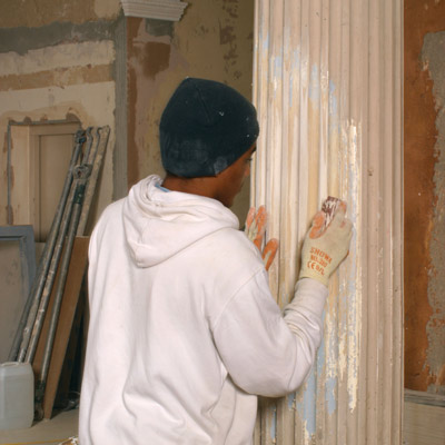 man stripping paint from column