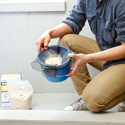 man sifting unused grout with wire mesh window screen scrap 