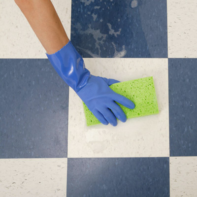 person scrubbing a tile floor with a sponge