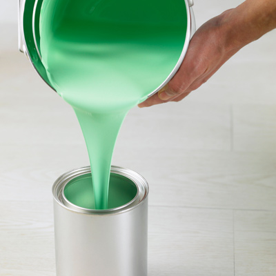 person pouring paint into a new paint can 