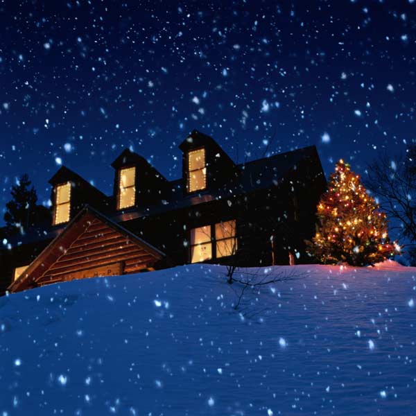 house with lit Christmas lights while it's snowing 